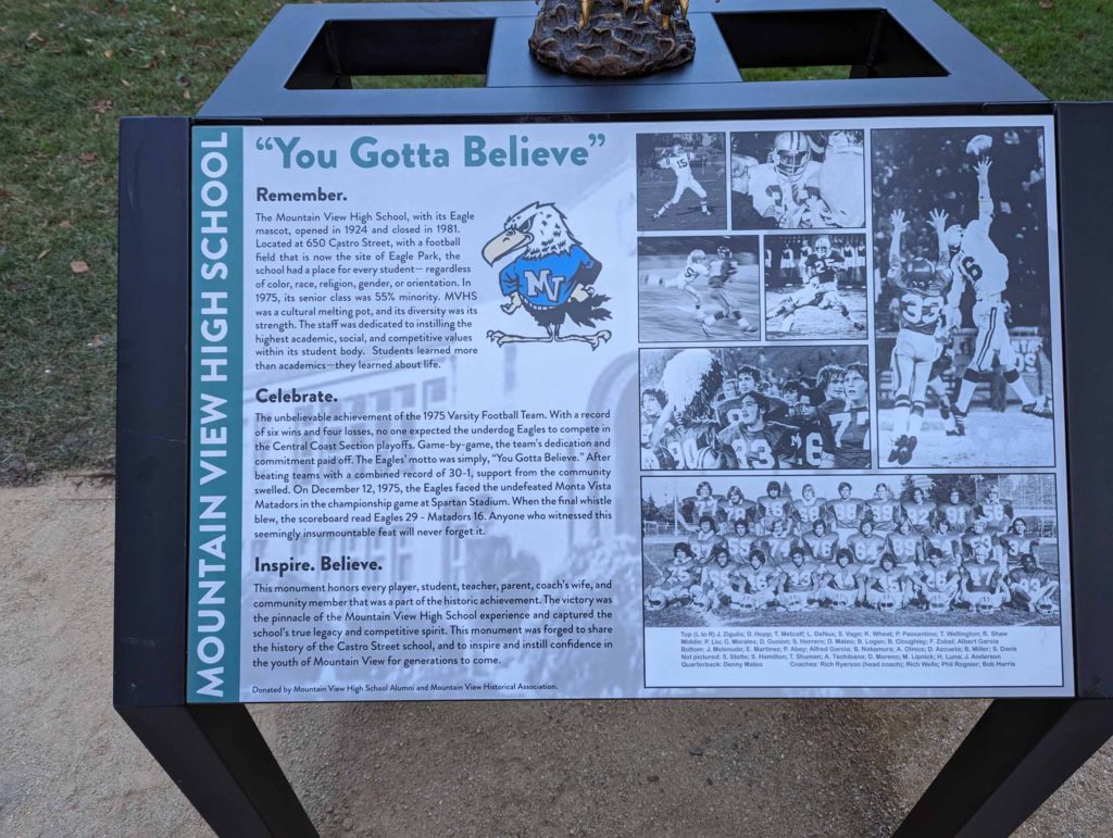 Interpretive sign under the eagle sculpture celebrating Mountain View Highschool's football championship in 1975 with black and white photos of the football team, and a large green title that says "You Gotta Believe".